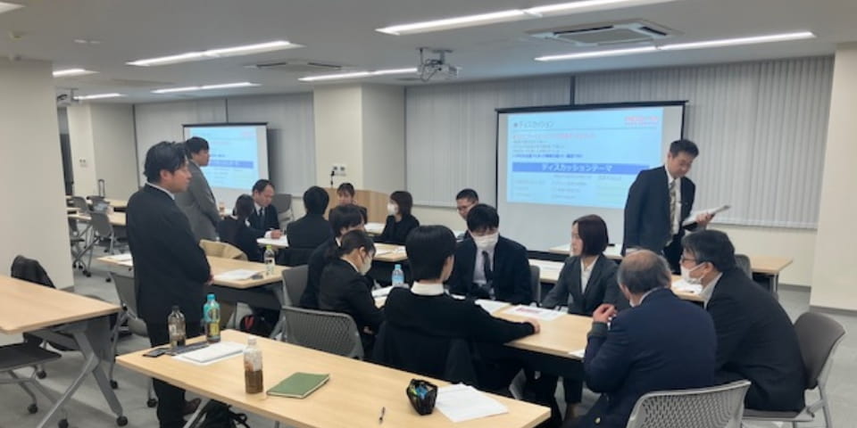 研修室で社員が講師の話を聞きながら学んでいる様子