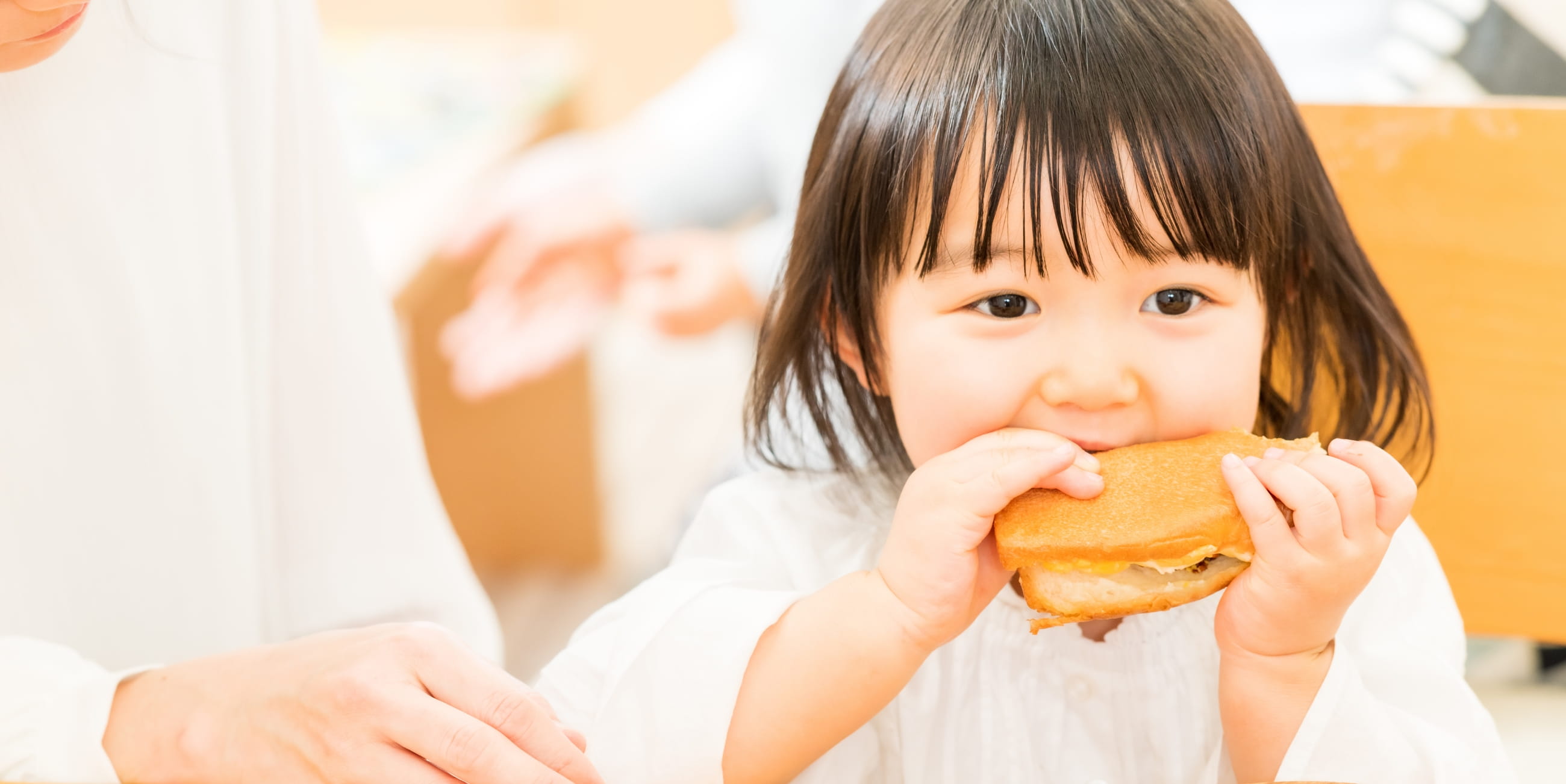 子供が両手でハンバーガーを食べている様子